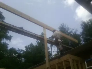 Carpenter setting a ridge beam over a new addition frame — Ice Dam Removal by Roofing Brothers in Plainwell
