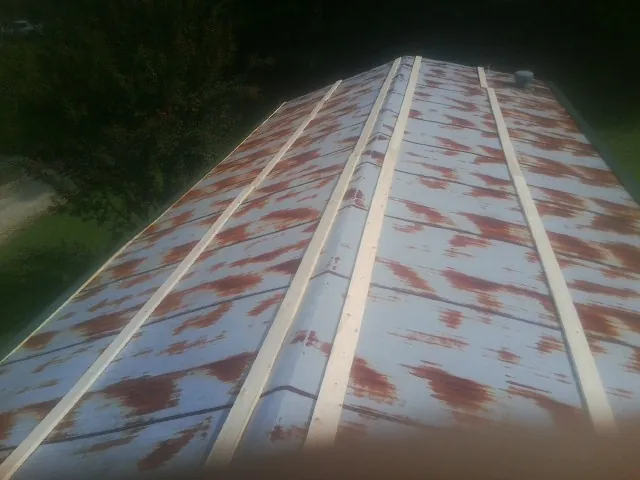 Rusted metal roof panels with new wood purlins before replacement — Storm Damage Roof Repair in Plainwell by Roofing Brothers
