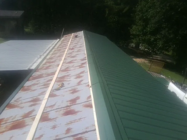 Old rusted panels beside newly installed green metal roofing — Wind Damage Roof Repair by Roofing Brothers in Plainwell