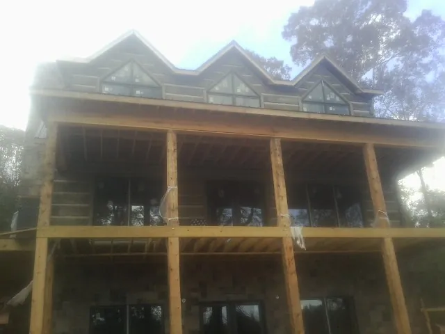 Dormers and porch framing on a large log home under construction — Roof Coating work by our crew in Plainwell