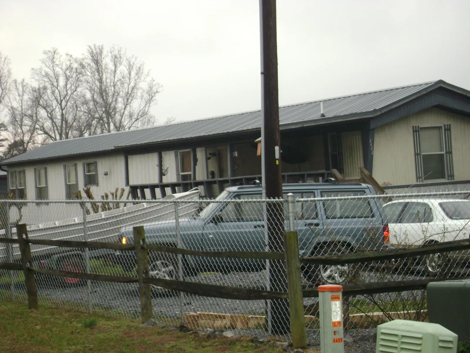Dark metal roof on a long single story building behind a chain link fence in Plainwell