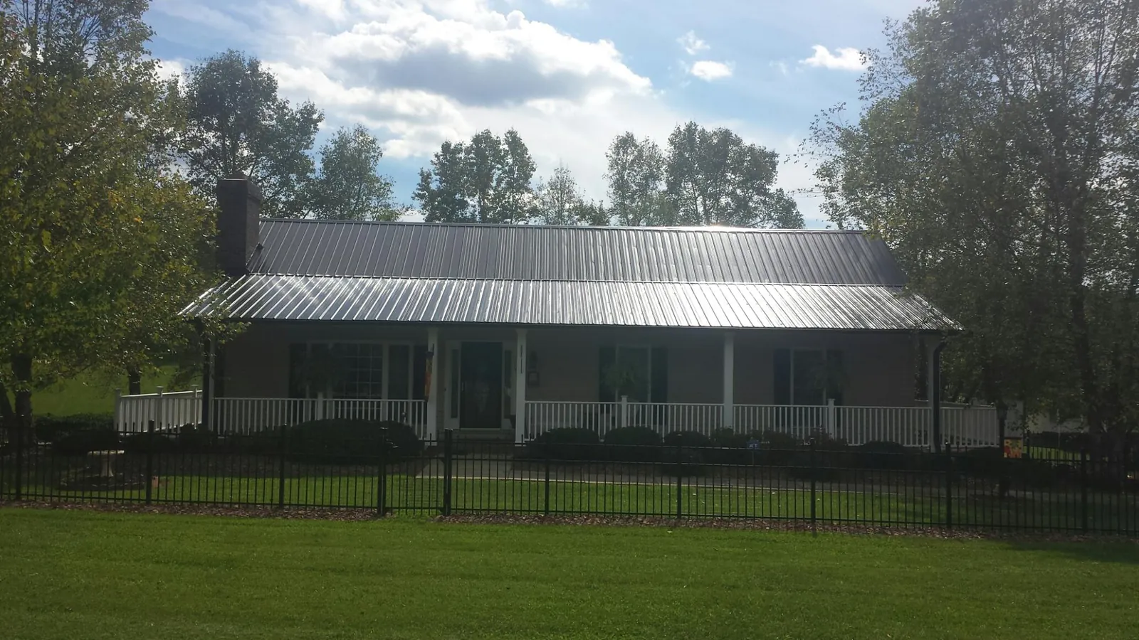 Gray metal roof on a brick ranch with a full width front porch — Gutter Guard Installation work by our crew in Plainwell