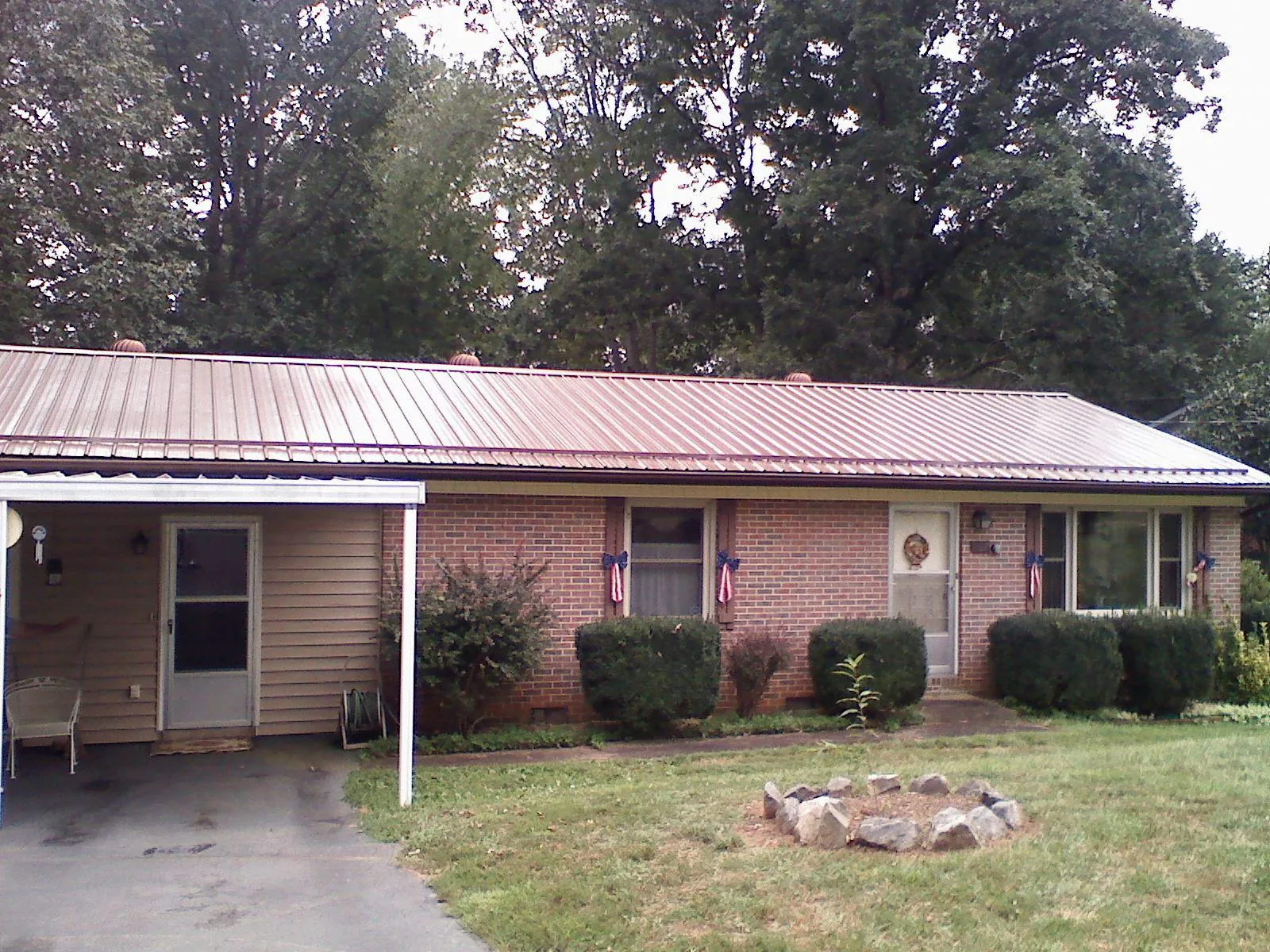 Bronze metal roof and carport on a brick ranch home — Roof Repair work by our crew in Plainwell