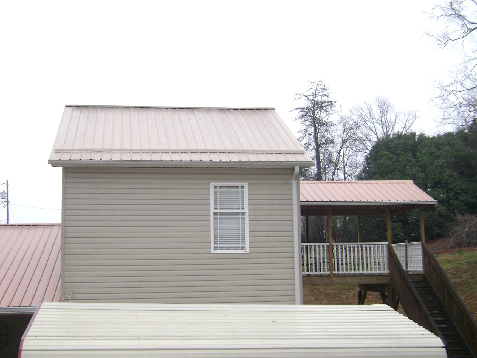 Tan metal roofs on a two story addition and attached porch, from a Roof Replacement job in Plainwell