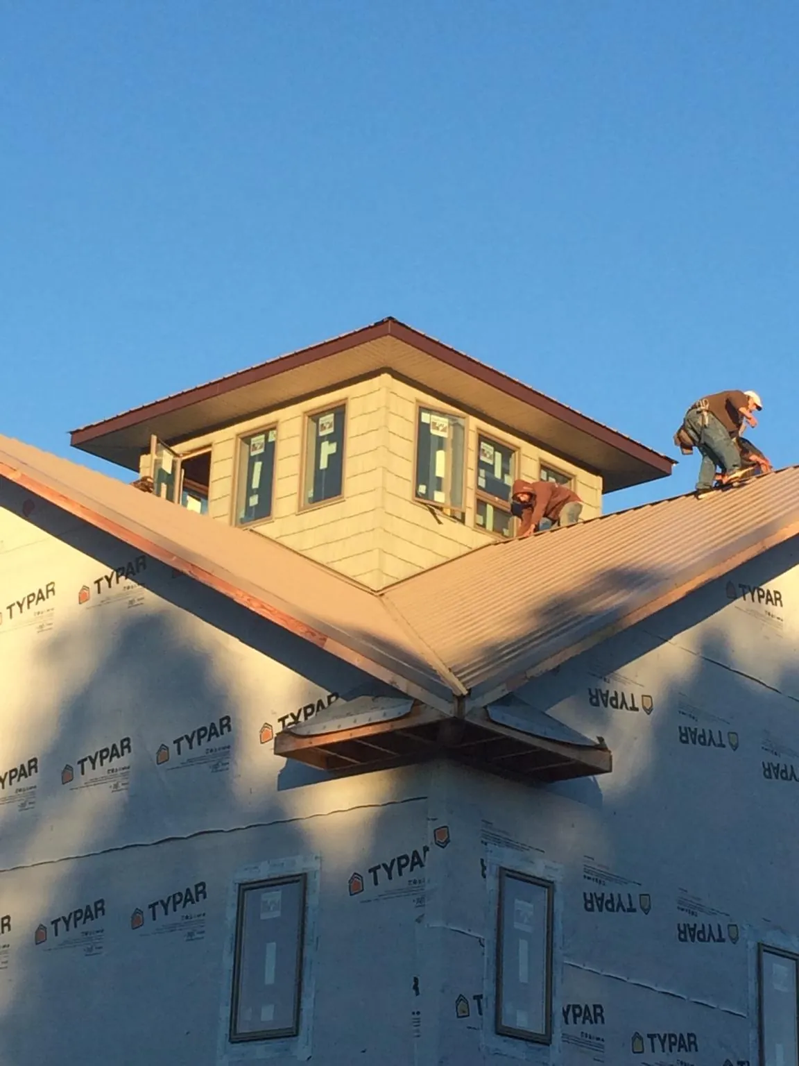 Roofers working around a rooftop cupola on a new metal roof at sunset — Roof Waterproofing in Plainwell by Roofing Brothers